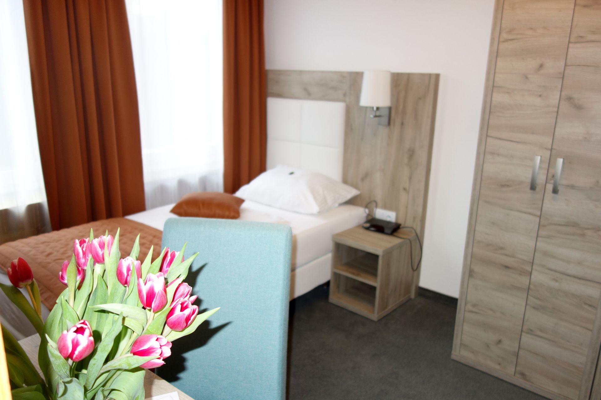 A hotel room with a single bed and a chair