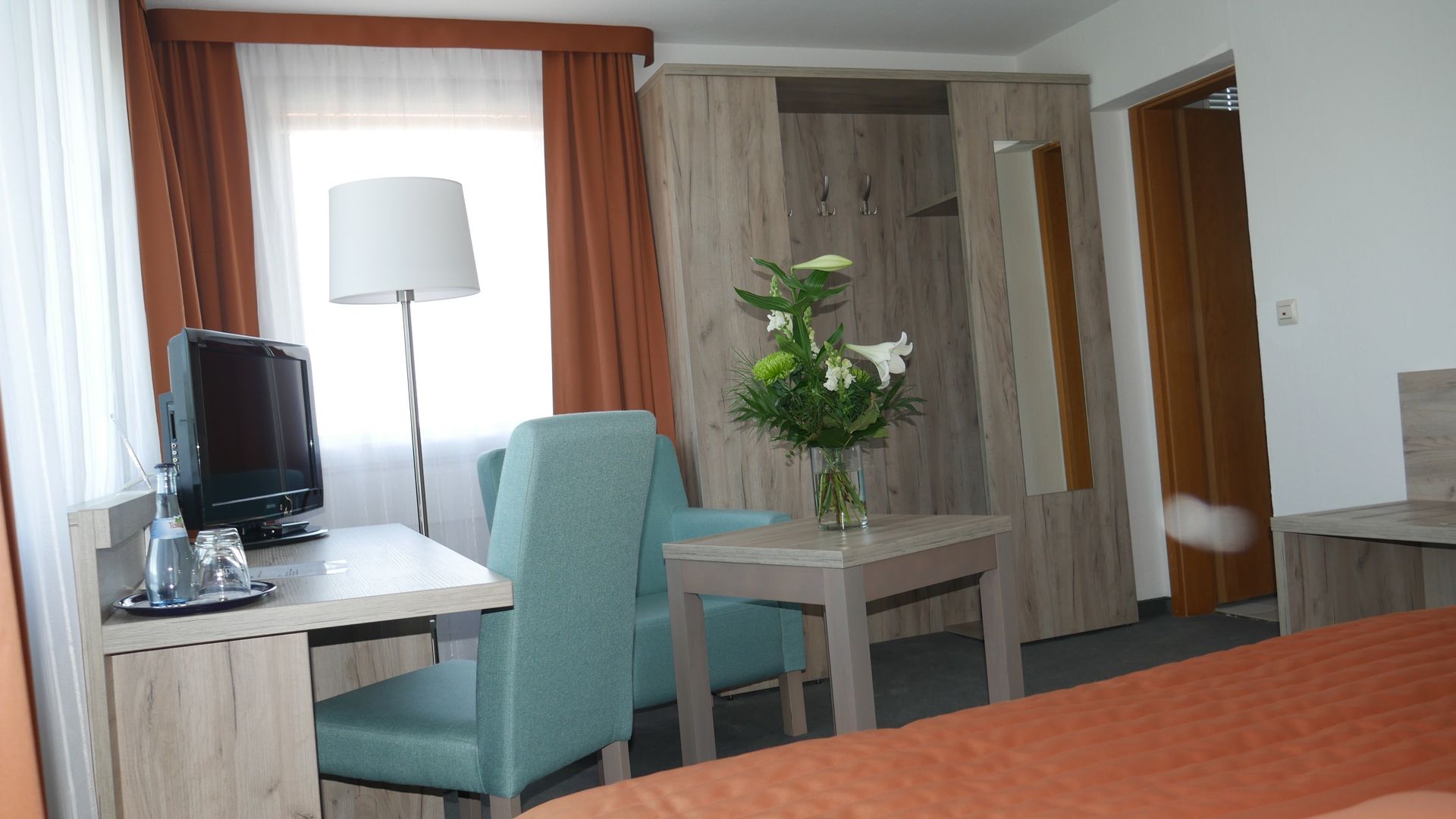 A hotel room with a desk and chairs and a vase of flowers