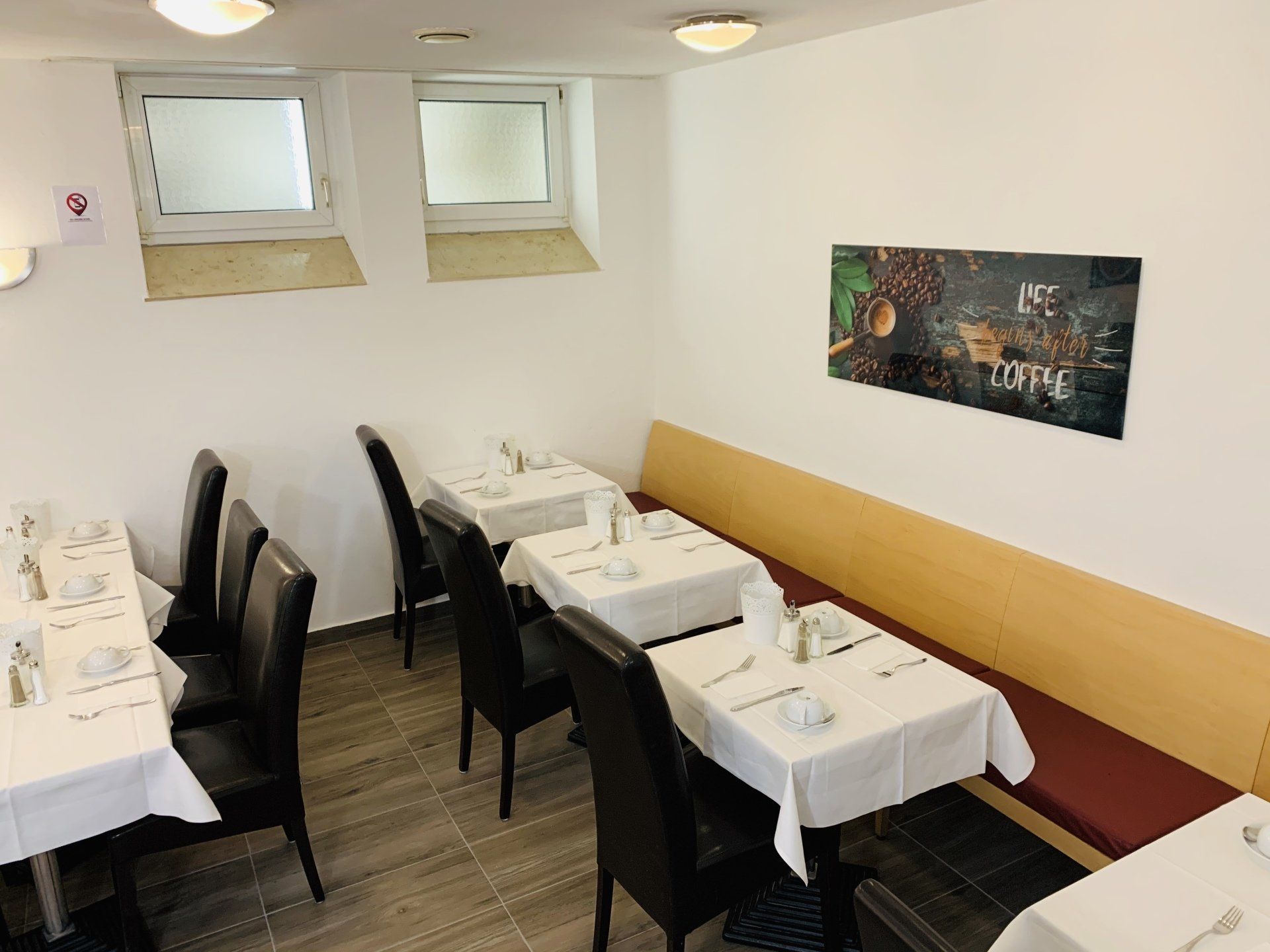 A restaurant with tables and chairs and a painting on the wall that says coffee