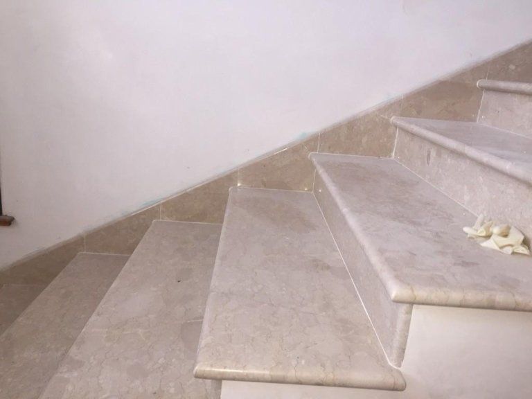 Un primo piano di una rampa di scale con un muro bianco sullo sfondo.