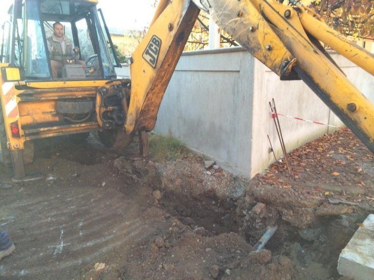 Un escavatore JCB giallo sta scavando una buca nel terreno
