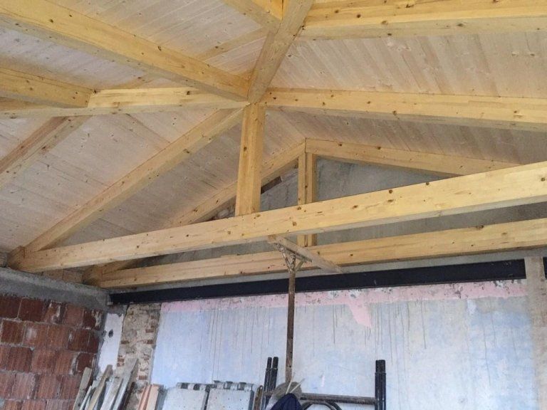 Una stanza con un soffitto in legno e una scala.