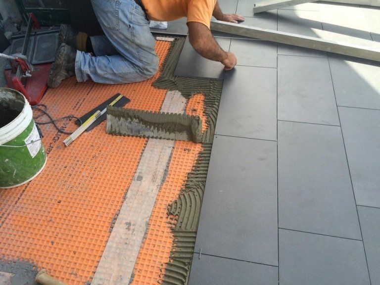 Un uomo sta posando delle piastrelle su un pavimento piastrellato