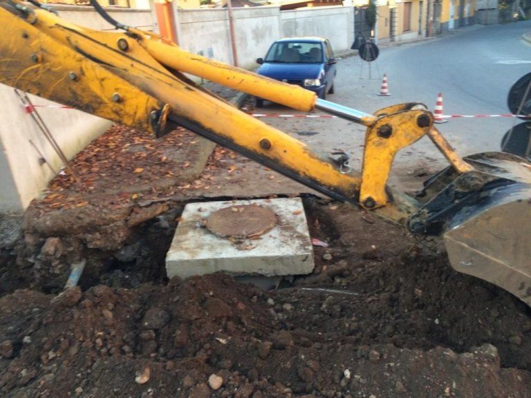Un escavatore giallo sta scavando una buca nel terreno