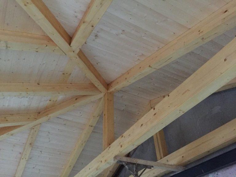 Un primo piano del soffitto di un edificio con travi in legno.