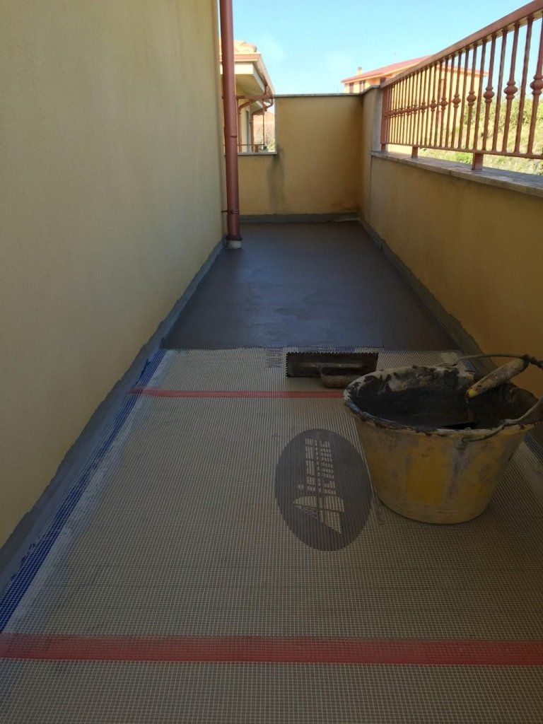 Un secchio di cemento è appoggiato su uno stuoia su un balcone.