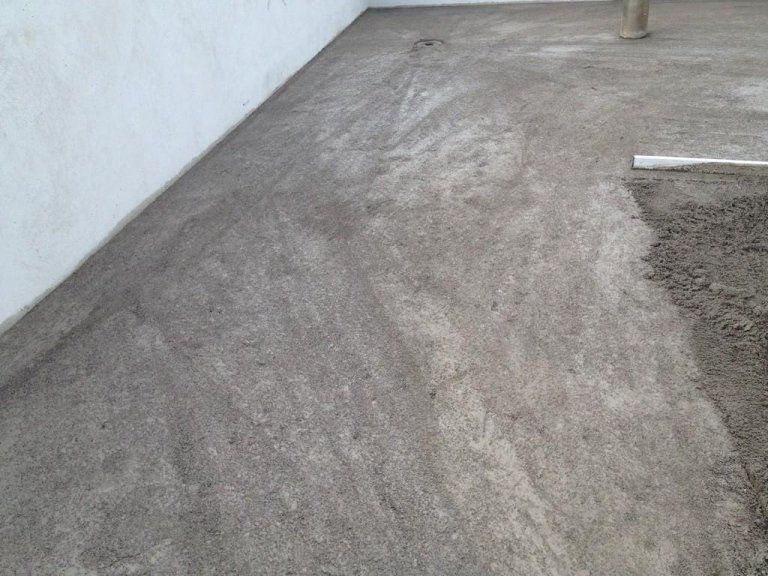 Una persona sta gettando del cemento sul pavimento di una stanza.