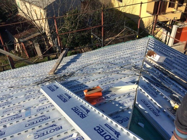 Una persona sta lavorando su un tetto su cui è scritto isotec