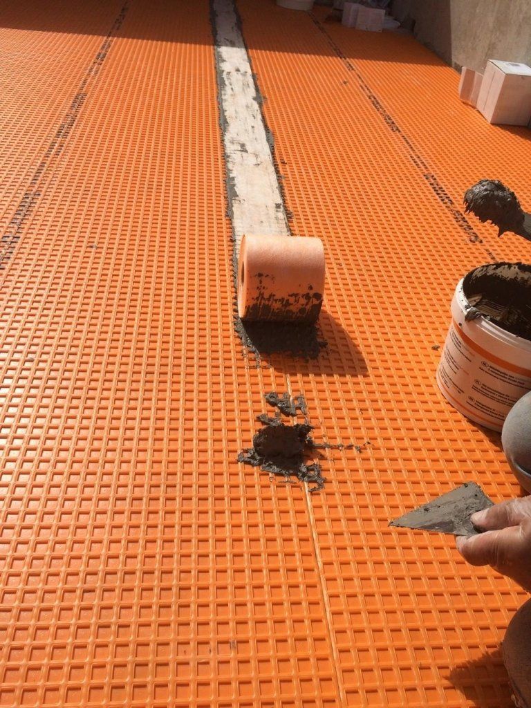 Una persona sta lavorando su un pavimento arancione con una spatola.