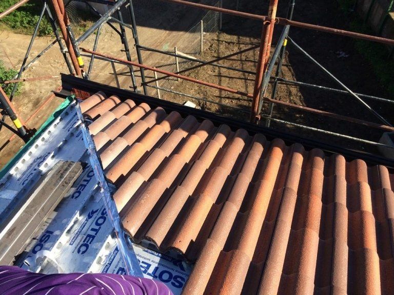 Una persona è in piedi su un tetto con sopra un qualche tipo di materiale di copertura