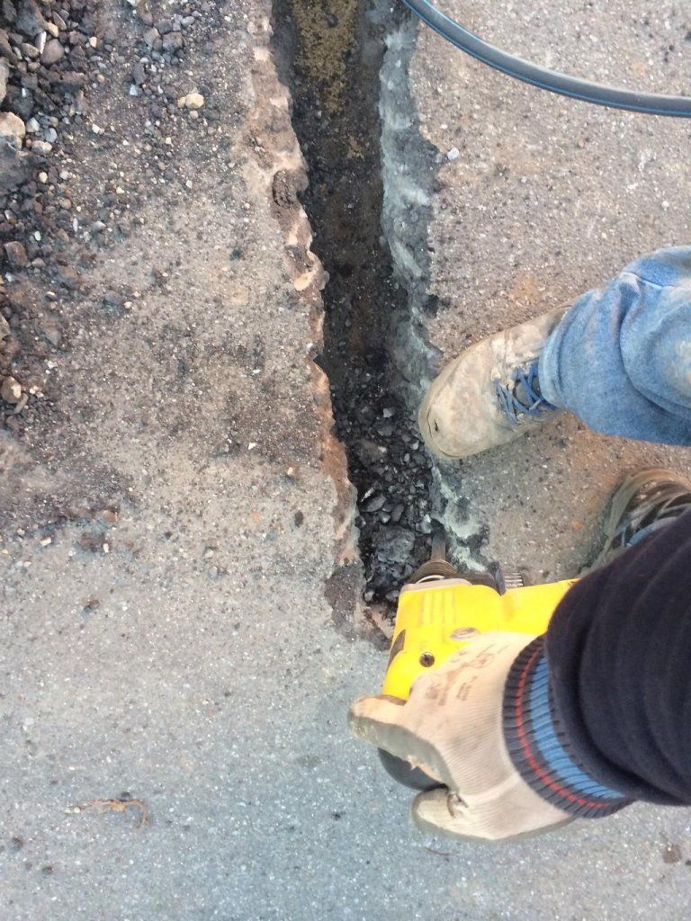 Una persona sta usando un attrezzo giallo per tagliare un buco nel terreno.