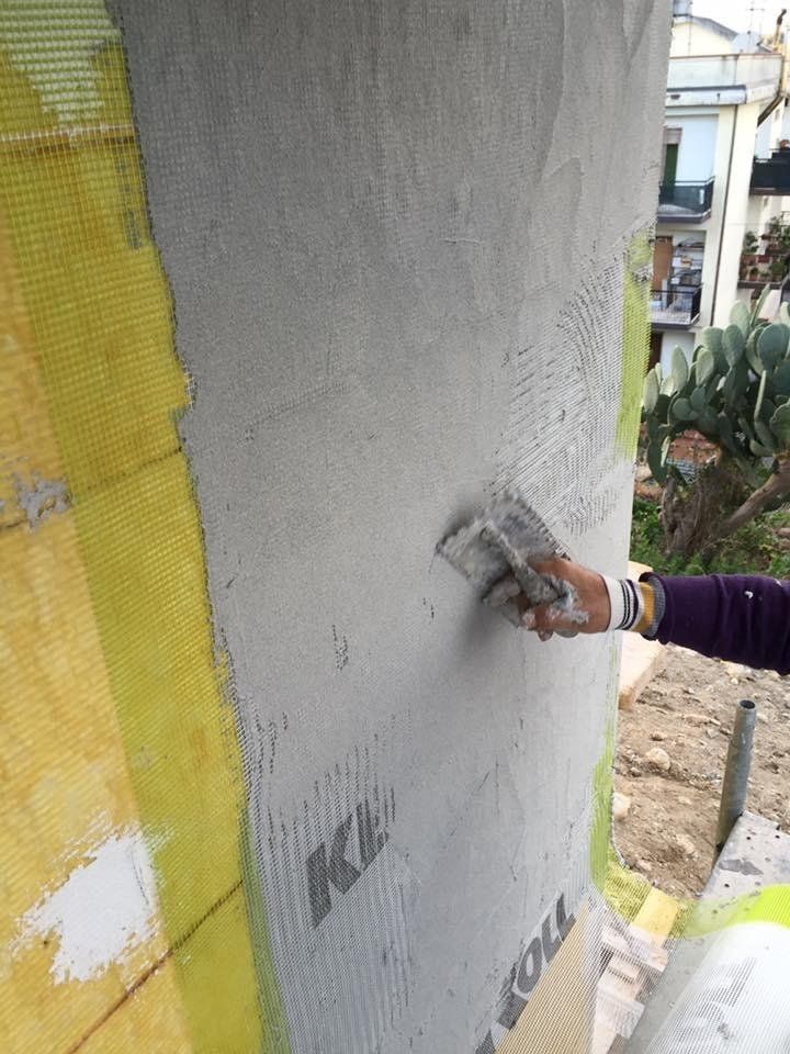 Una persona sta intonacando un muro con una cazzuola.
