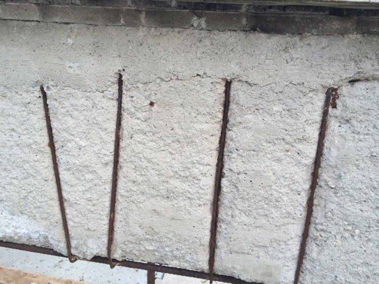 Primo piano di un muro di cemento con barre di metallo.