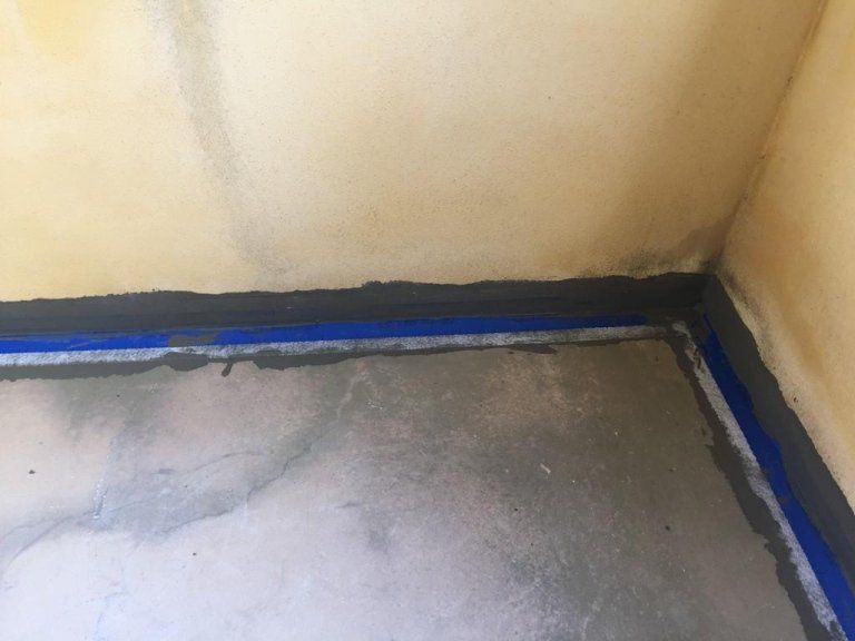 Un angolo di una stanza con un nastro blu sul pavimento.