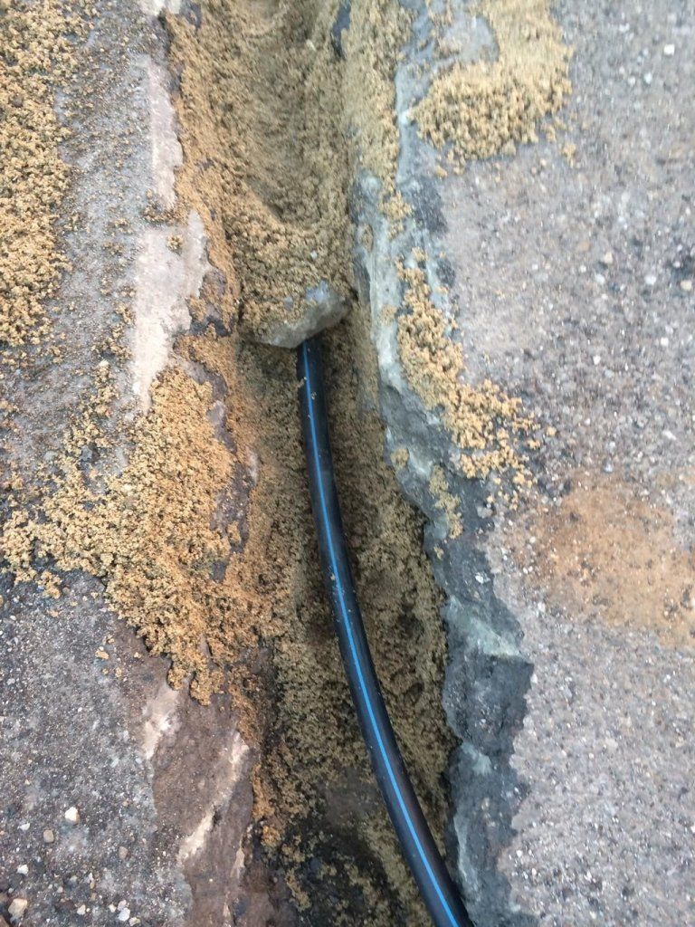 Un tubo nero spunta da un buco nel terreno.