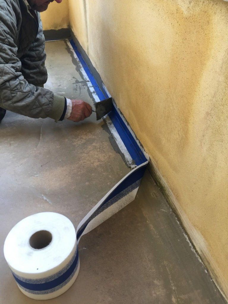 Un uomo sta lavorando su un muro con un rotolo di nastro adesivo.
