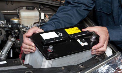 mechanic removing the battery from the car