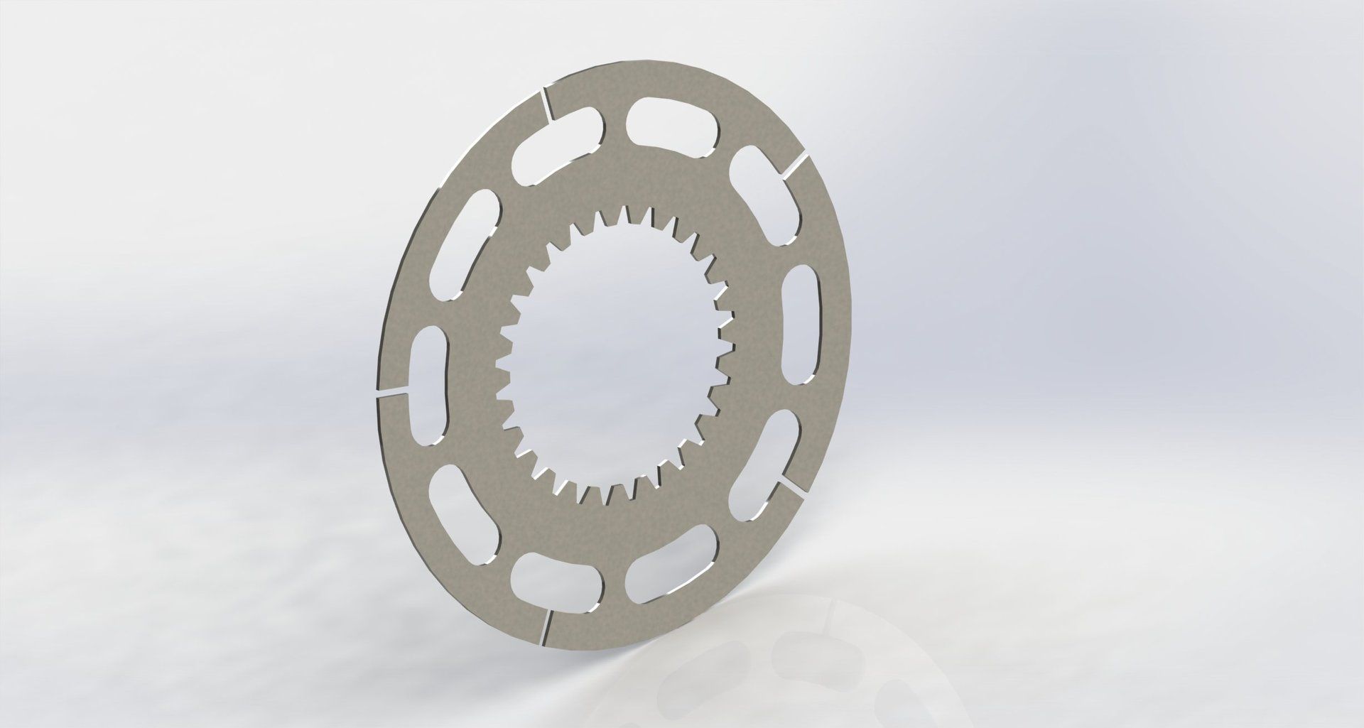 Circular metal disc with an inner gear and outer slotted ring.