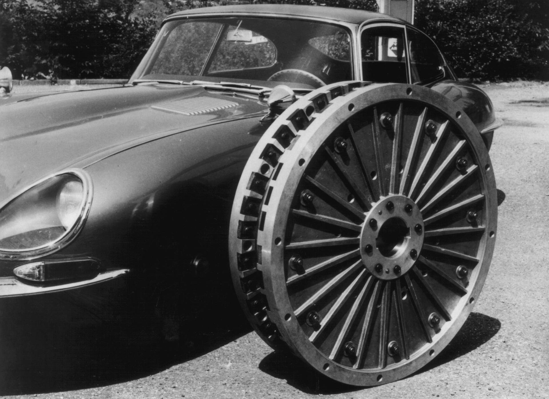 Klassischer Jaguar-Sportwagen mit einem großen, aufwendig gestalteten Rad, das daran lehnt.