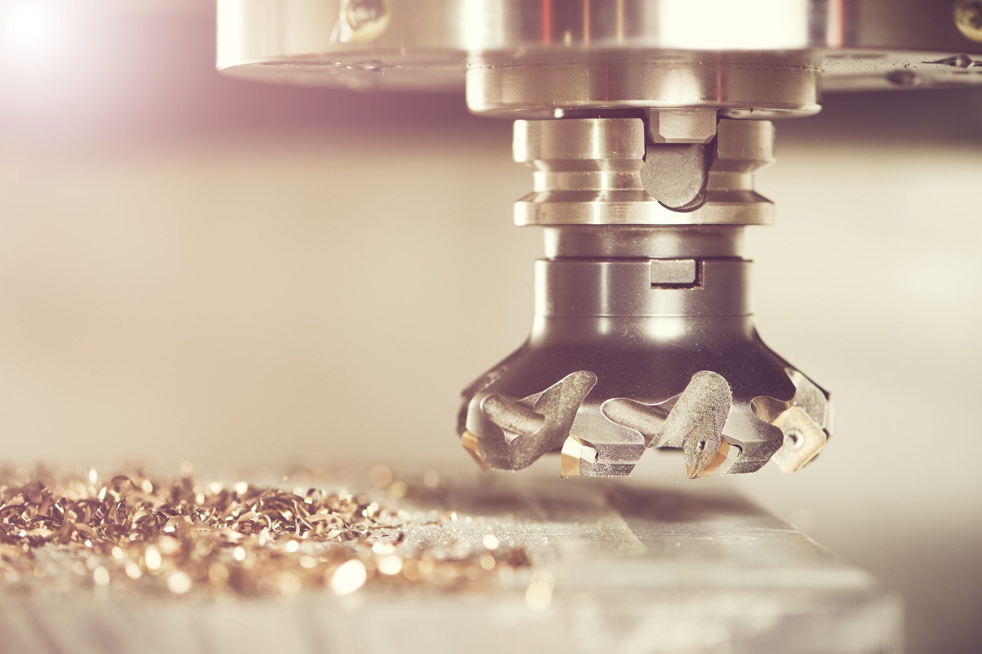 Nahaufnahme einer CNC-Fräsmaschine im Betrieb, die Metall schneidet und goldene Späne erzeugt.