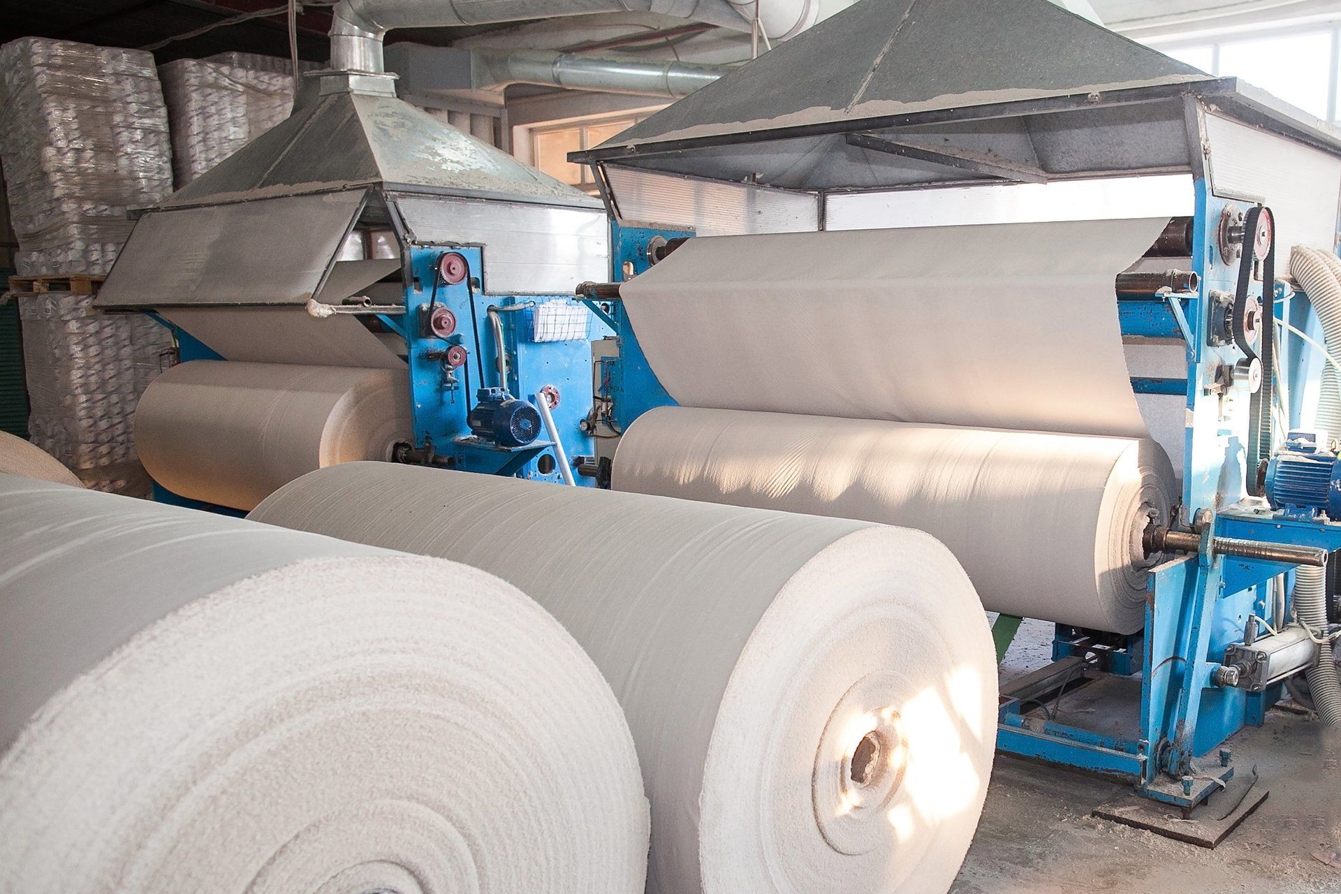 Papierrollen an einer Produktionsmaschine, möglicherweise in einer Papierfabrik.