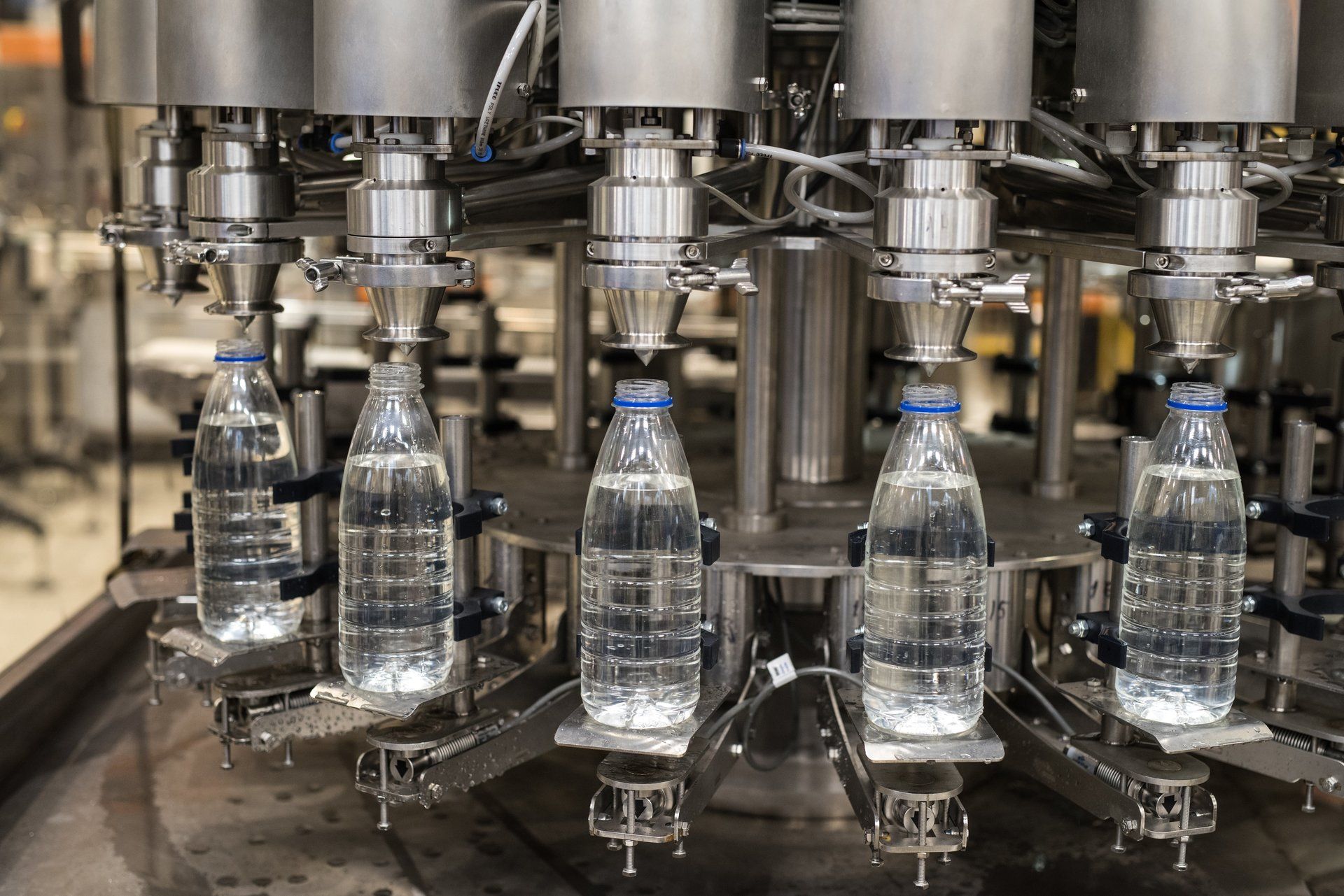 Abfüllmaschine füllt durchsichtige Plastikwasserflaschen mit einer klaren Flüssigkeit.