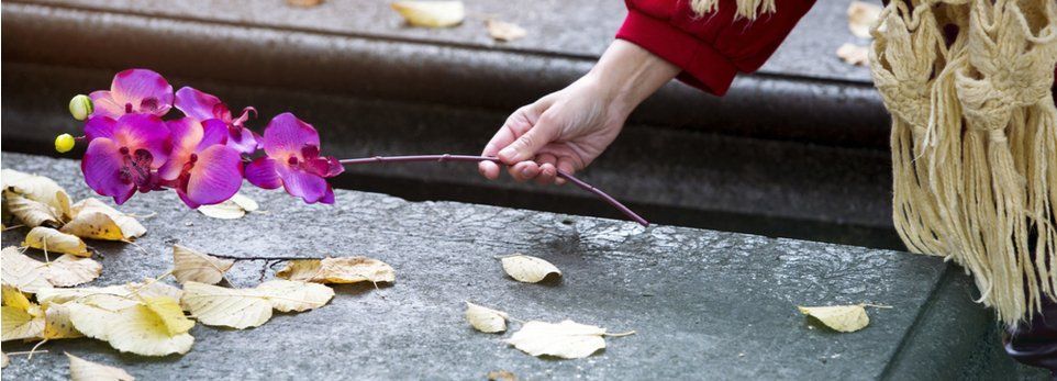 donna posa un fiore su una lapide