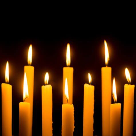Diverse candele gialle accese su uno sfondo nero