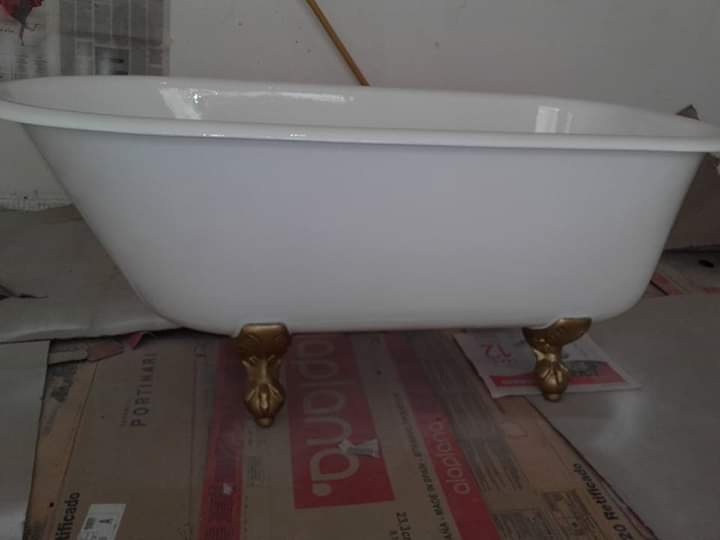 Bañera con patas de color blanco y pies de color dorado, apoyada sobre cartón.