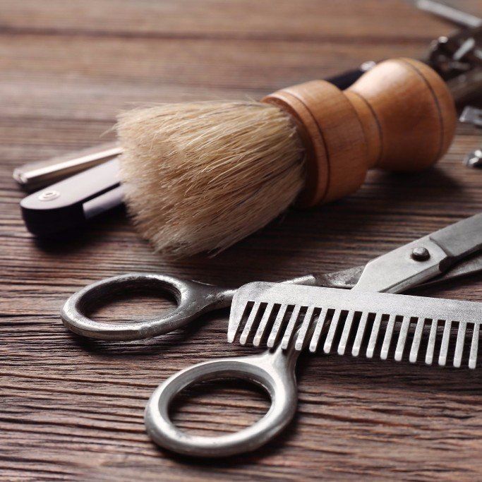 En saks, en kam og en barberkost på et træbord