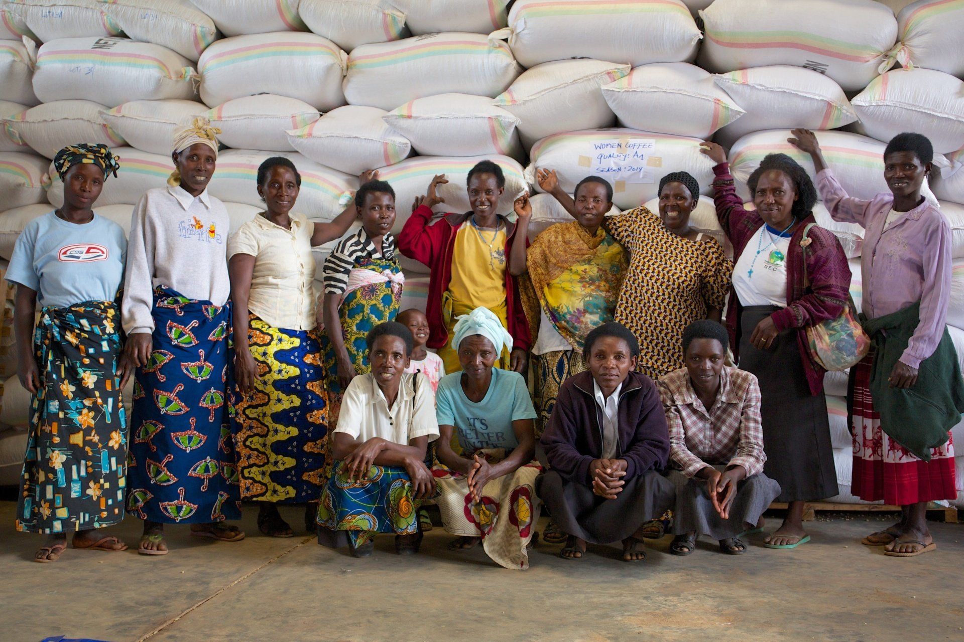 A group of women are posing for a picture in front of a wall of coffee bags