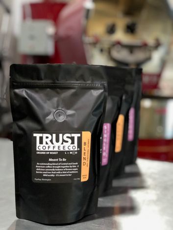 Four bags of trust coffee are lined up on a counter
