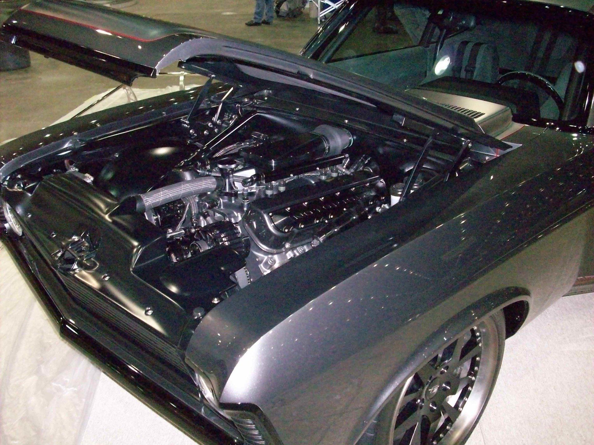 A black car with the hood up and the engine exposed