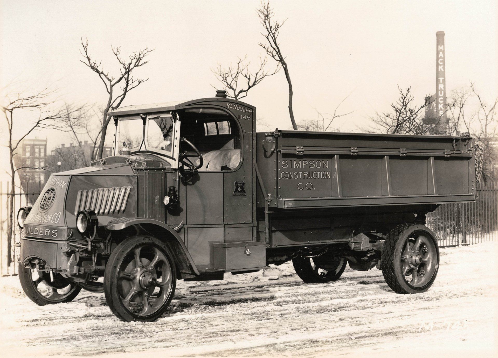 A black and white photo of an old dump truck in the snow