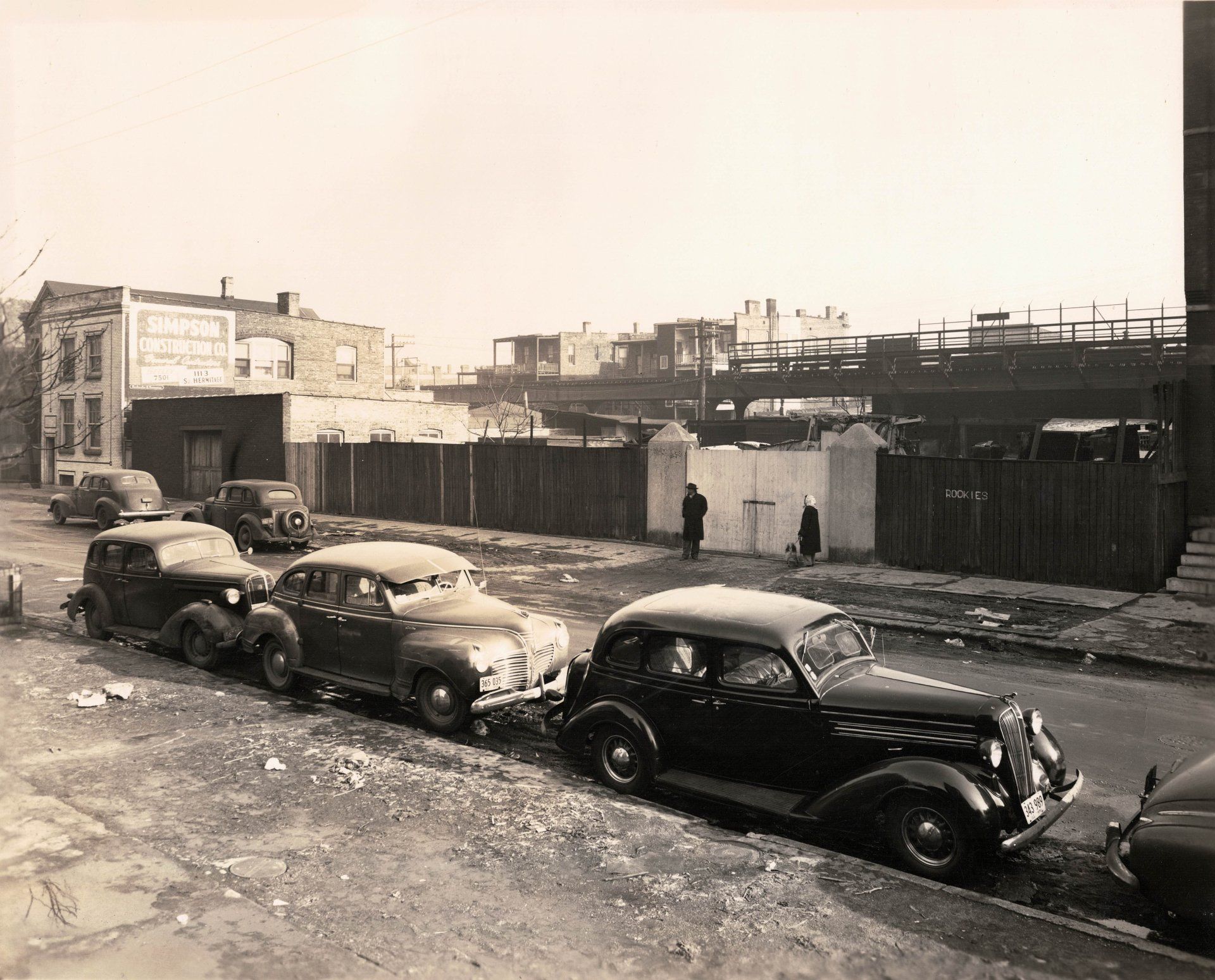 A black and white photo of cars parked on the side of the road