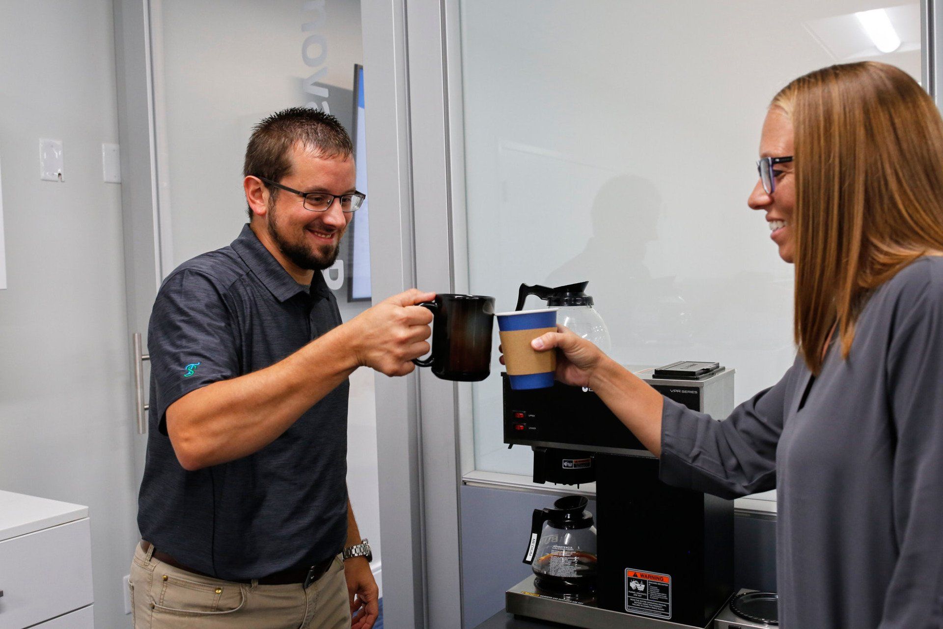 Two TrueScripts employees clinking their coffee mugs together
