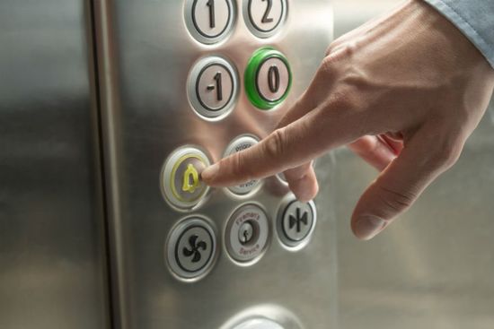 uomo che preme pulsante allarme di un ascensore
