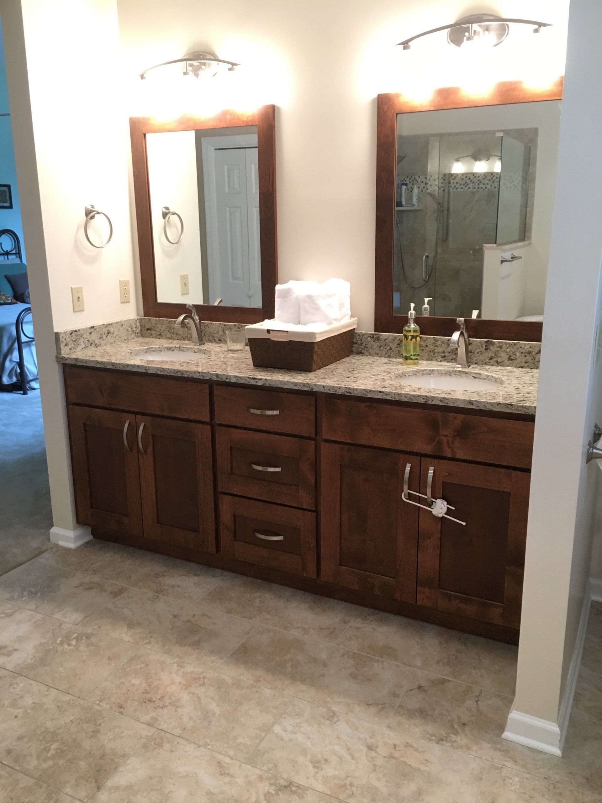 Bathroom vanity with dark wood cabinets, granite countertop, and two mirrors.