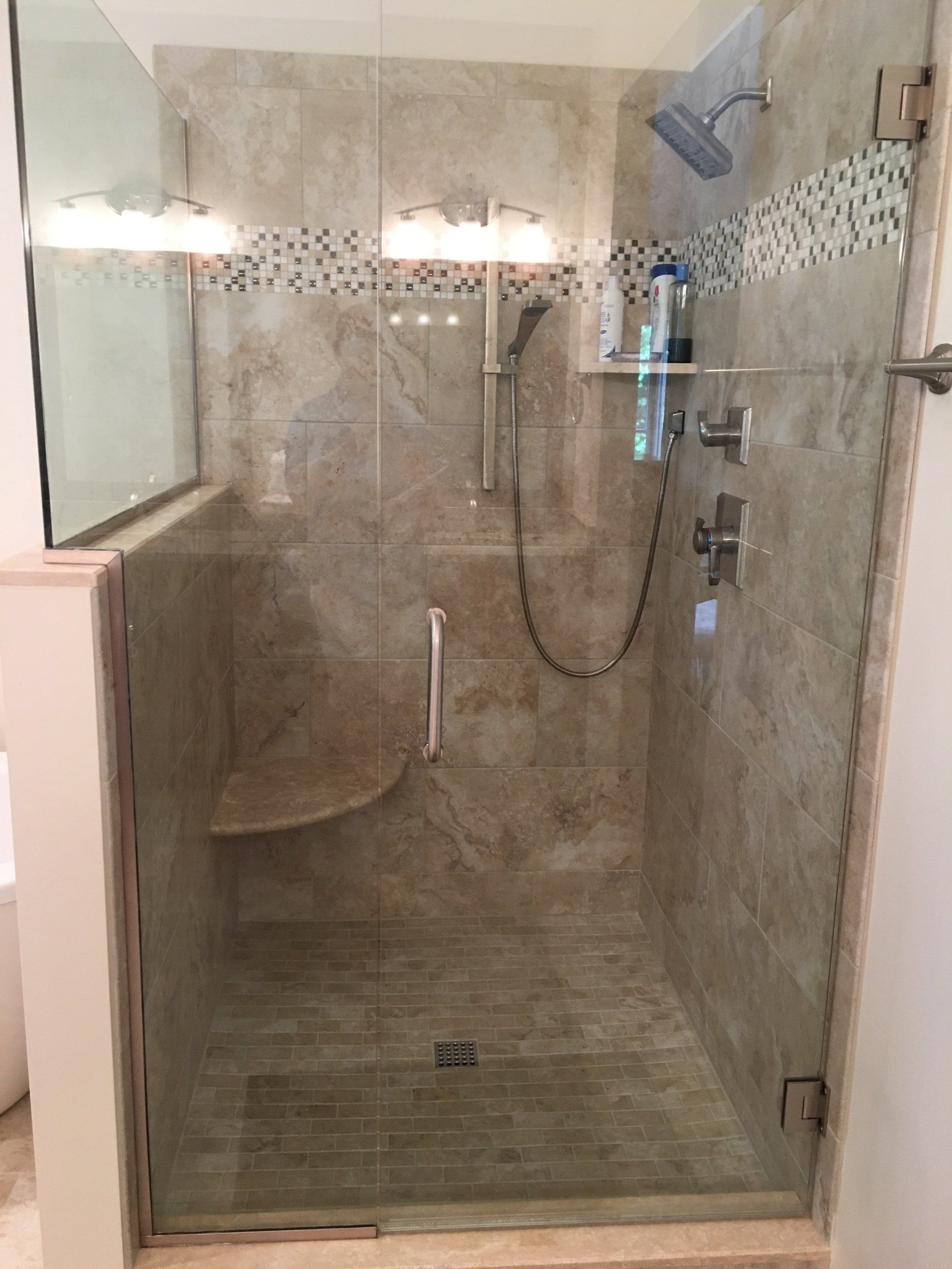 Shower with glass door, beige tile, and silver shower fixtures.
