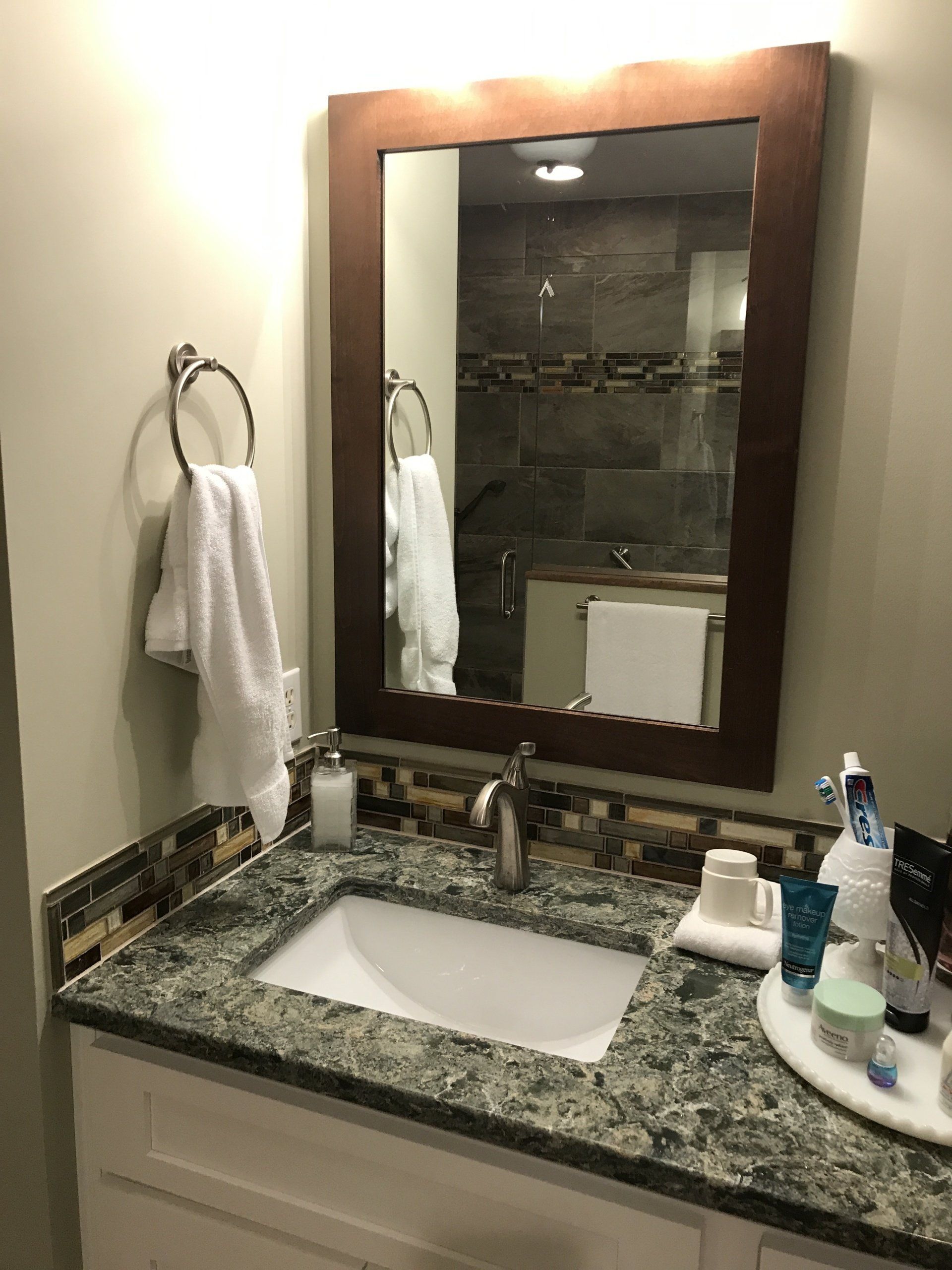Bathroom sink with mirror, towel ring, and toiletries on the countertop.