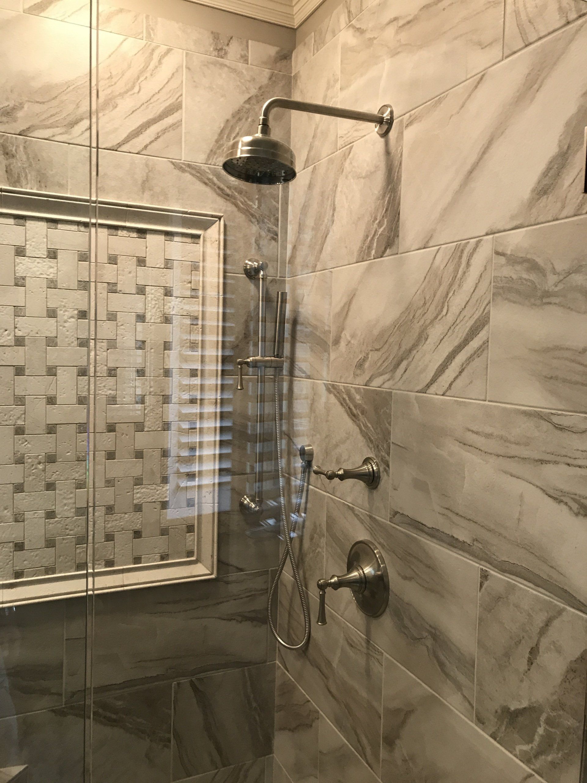 Shower with marble tile and silver fixtures.