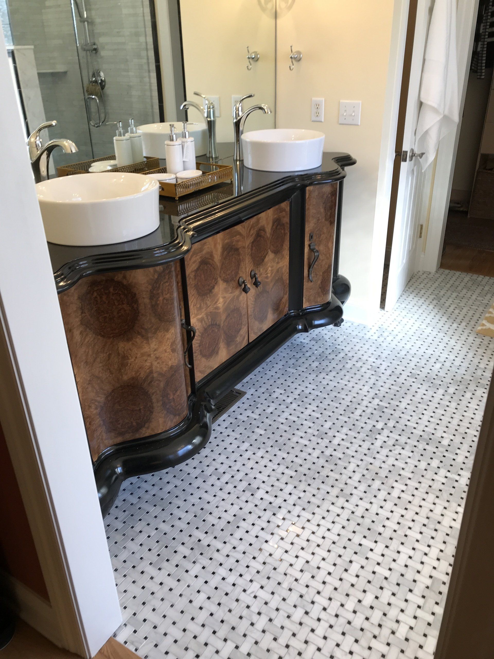 Bathroom with a dark wooden vanity, white sinks, and penny tile flooring.