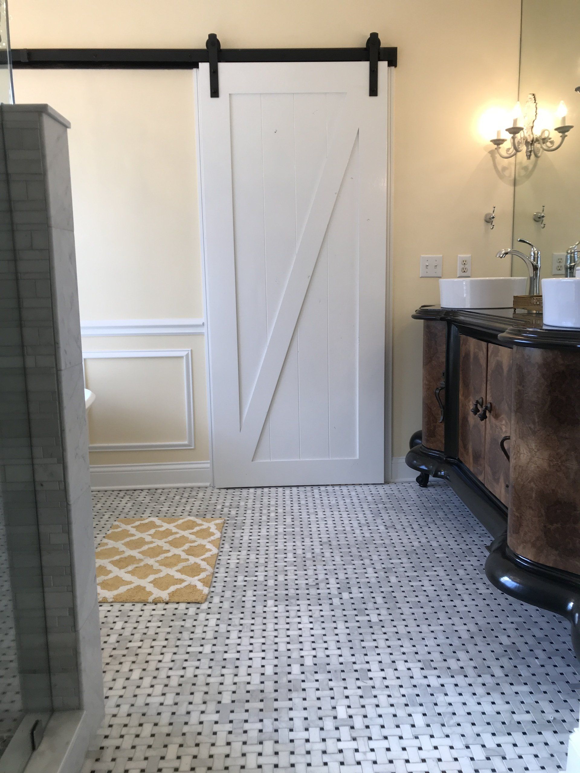 Bathroom with a white sliding barn door, patterned tile floor, and a double vanity.