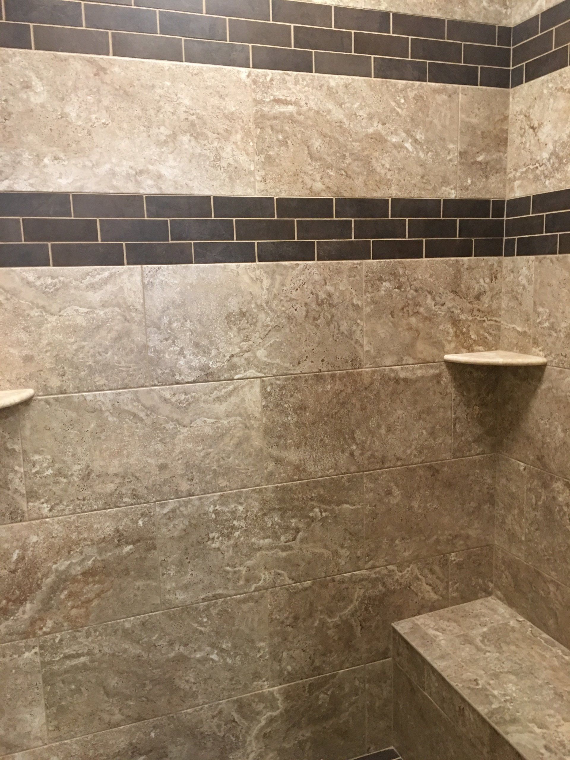 Shower with beige and brown tile; bench and shelves are built-in.