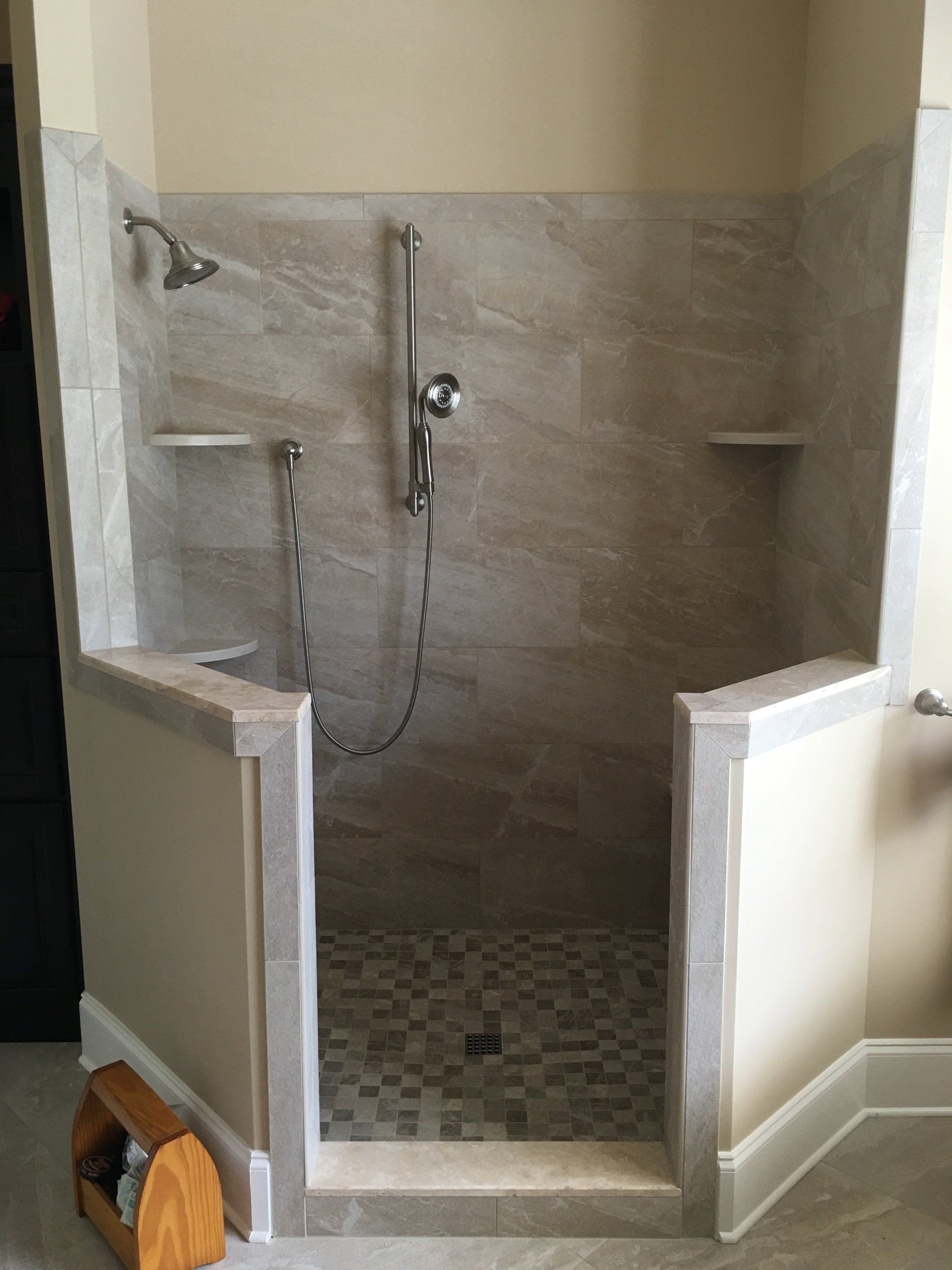 Walk-in shower with beige walls, tiled floor, and built-in shelves. Chrome shower fixtures.