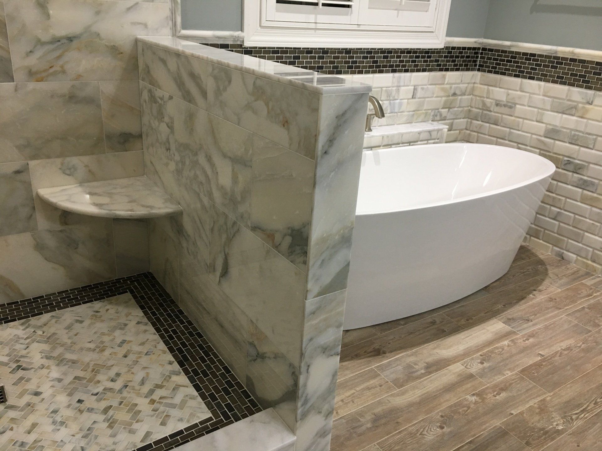 Bathroom with marble shower and freestanding white tub.