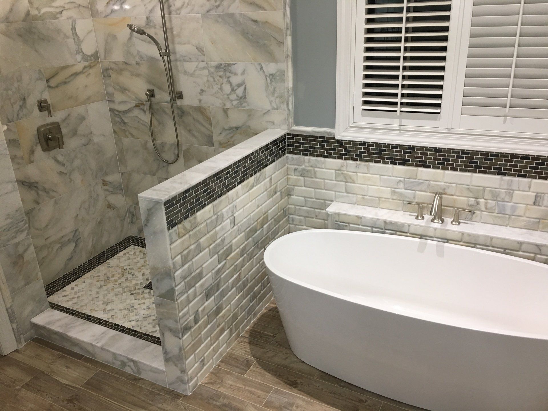 Bathroom with a white soaking tub, shower, and marble tiles.