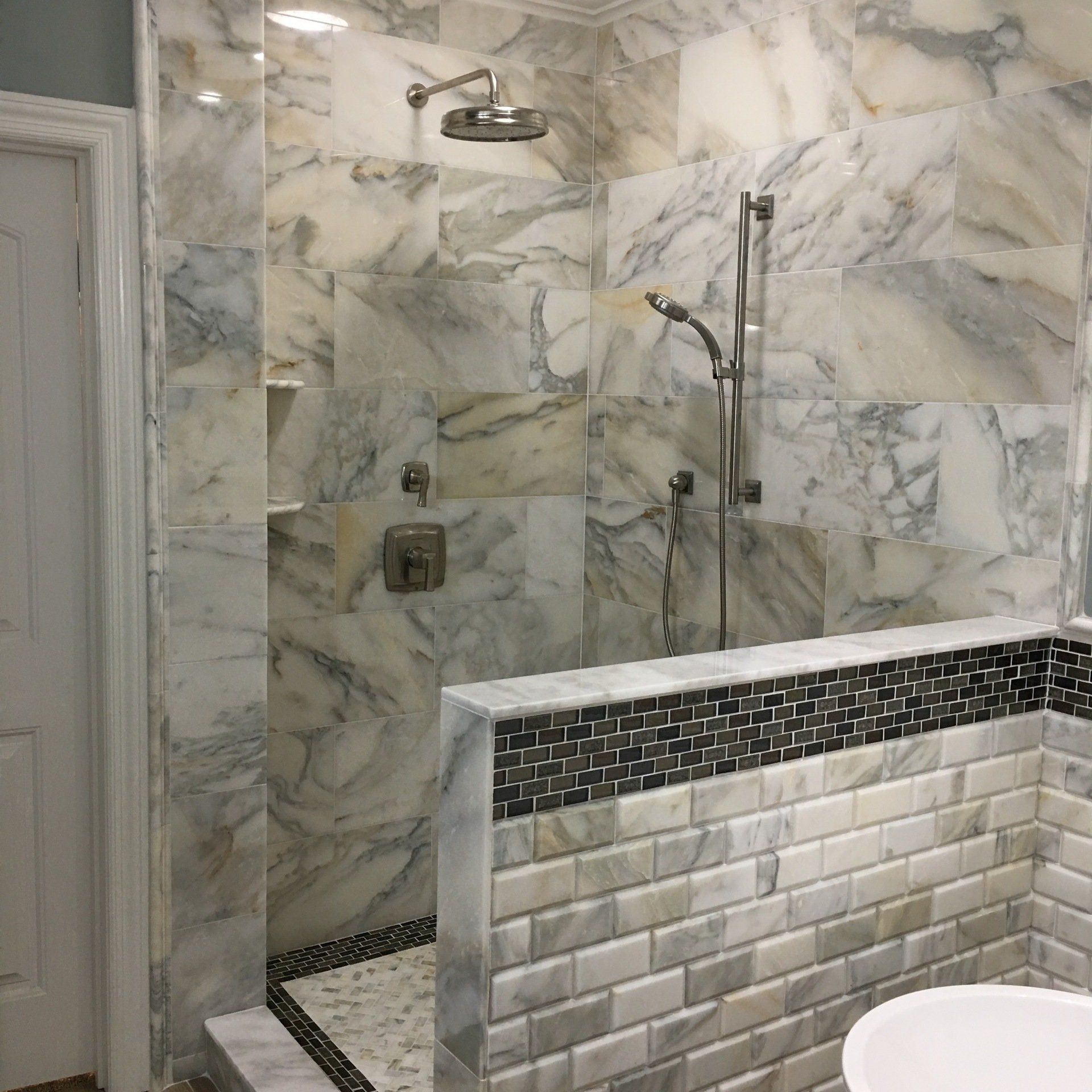 Bathroom with marble tile shower and accent wall with black and white tile.