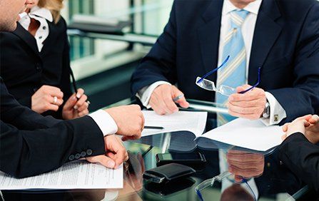 Visa Law Attorneys — People in Business Suits With Paperwork at Desk in Duluth, GA Visa Law Attorneys — People in Business Suits With Paperwork at Desk in Duluth, GA
