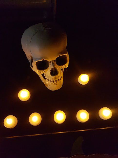Decoratie met een schedel, hangend boven brandende kaarsen, donkere achtergrond.